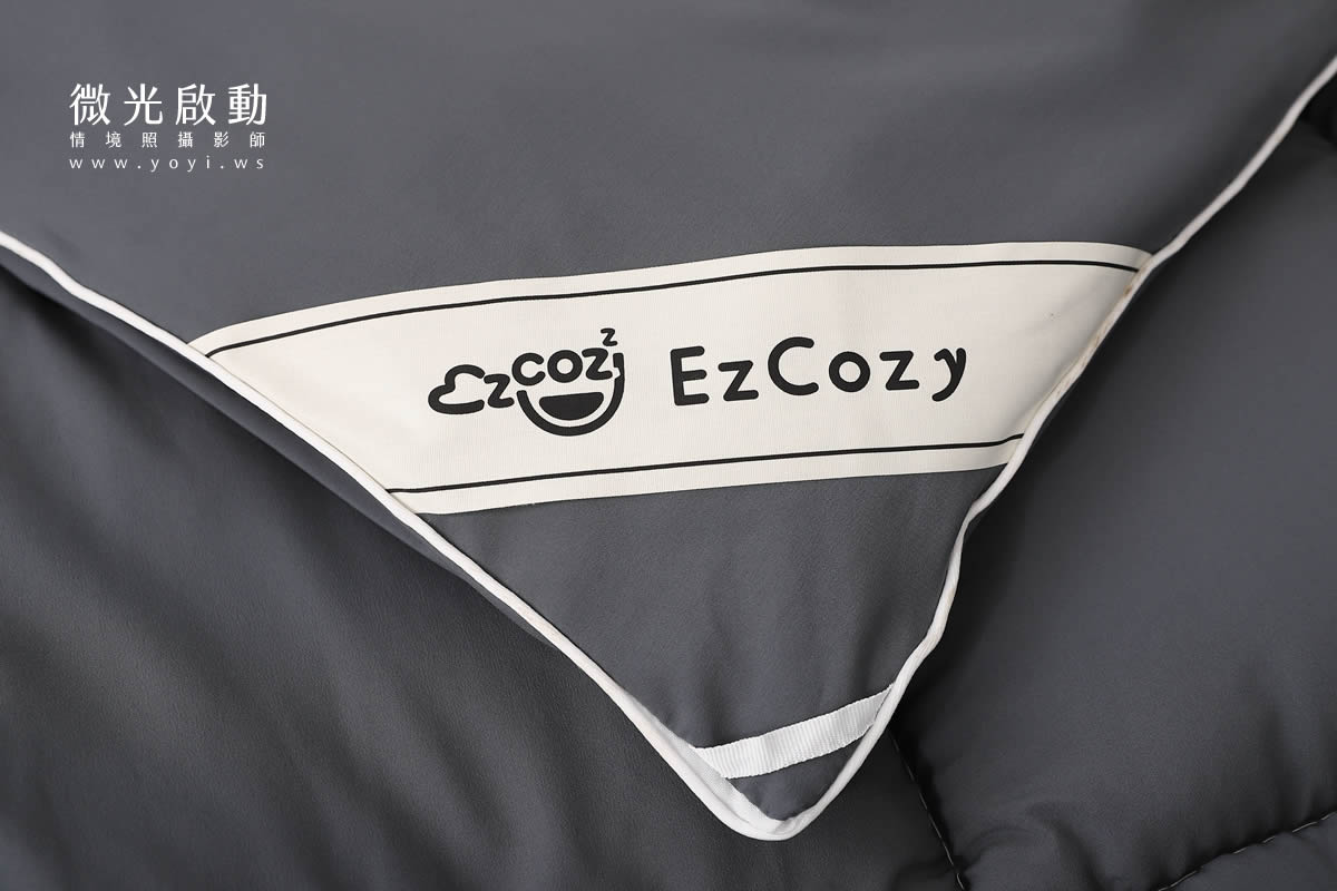 商品攝影作品。灰色寢具在簡約的臥室環境中，搭配木質家具和裝飾品，呈現現代感。適用於寢具攝影、專業攝影。
