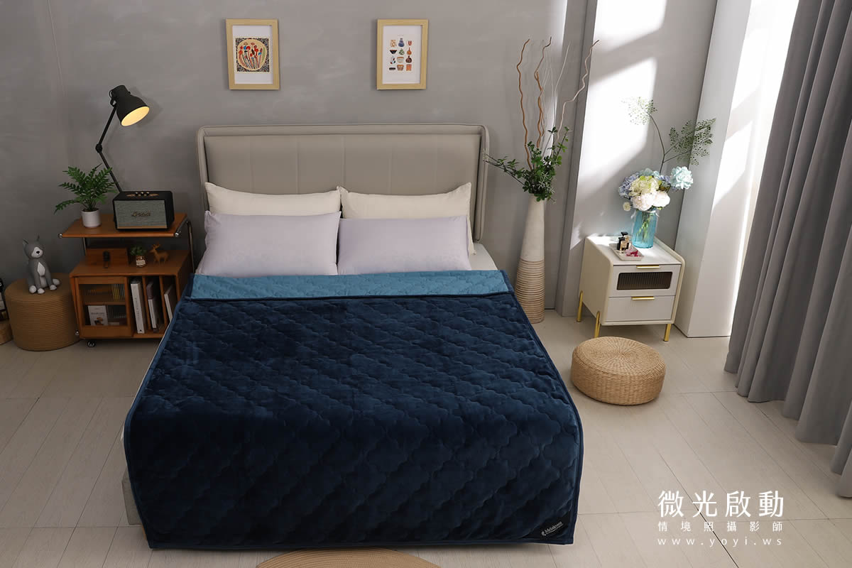 深藍色絎縫毛毯平鋪於床上，搭配灰色調臥室，簡潔大方，床墊商品拍攝