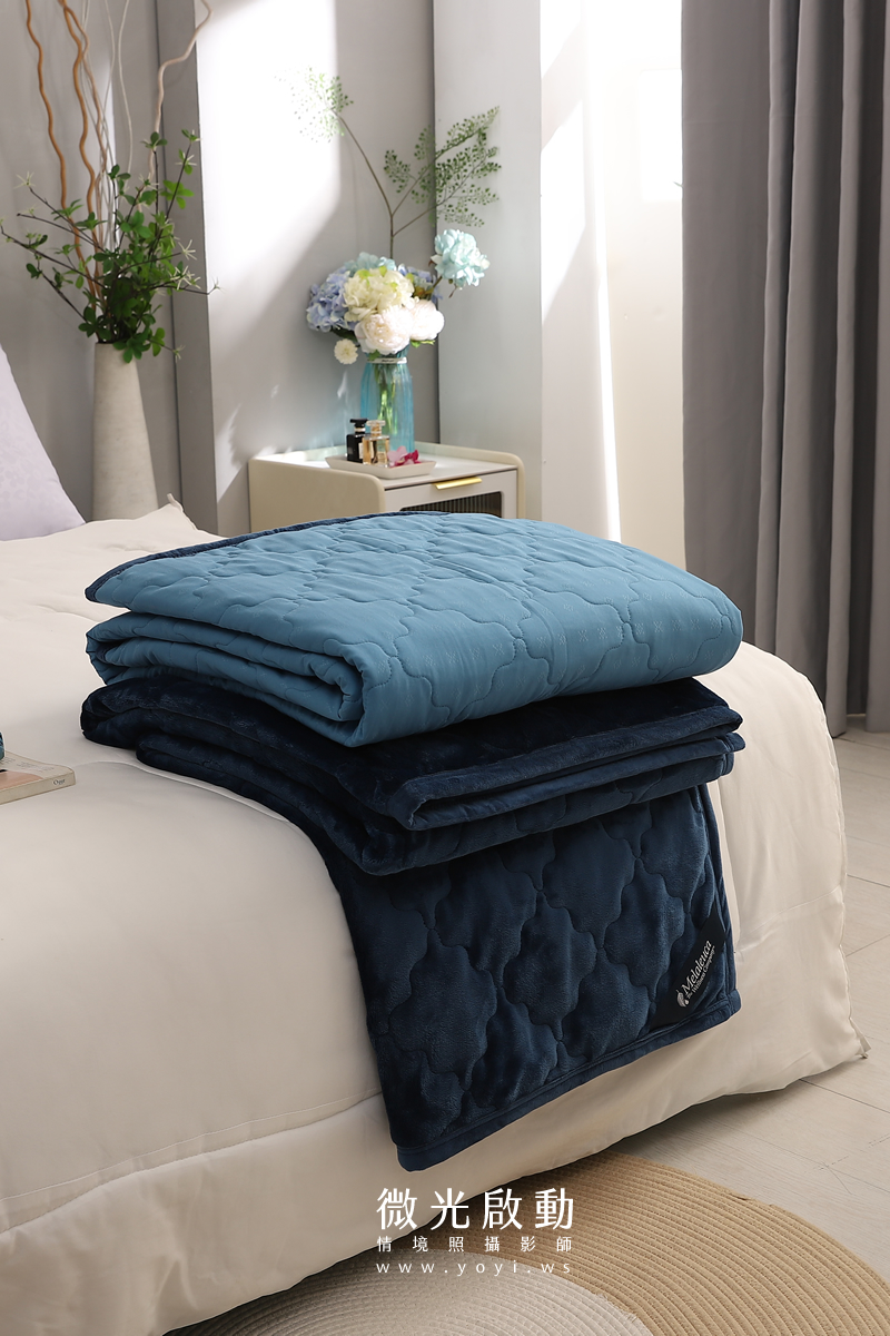 堆疊的藍色絎縫毛毯，展現產品厚度與柔軟度，適合商品細節特寫